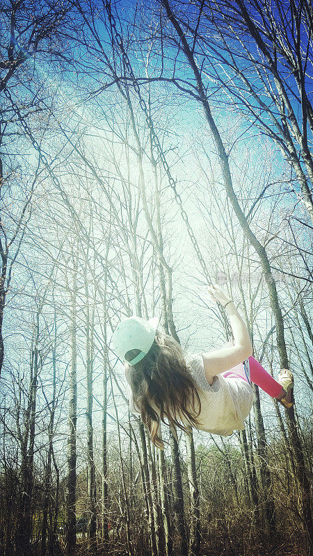 Long Haired Girl Swinging on Swing with Trees